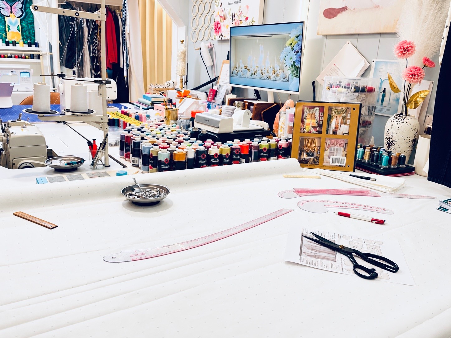 Cutting table, measuring tools, and thread collection inside the atelier.