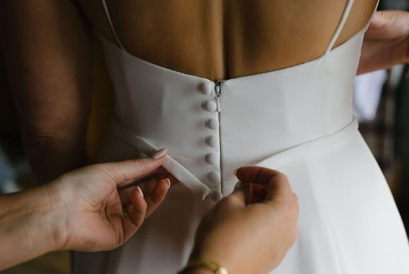 Hands adjusting the back of a white dress.