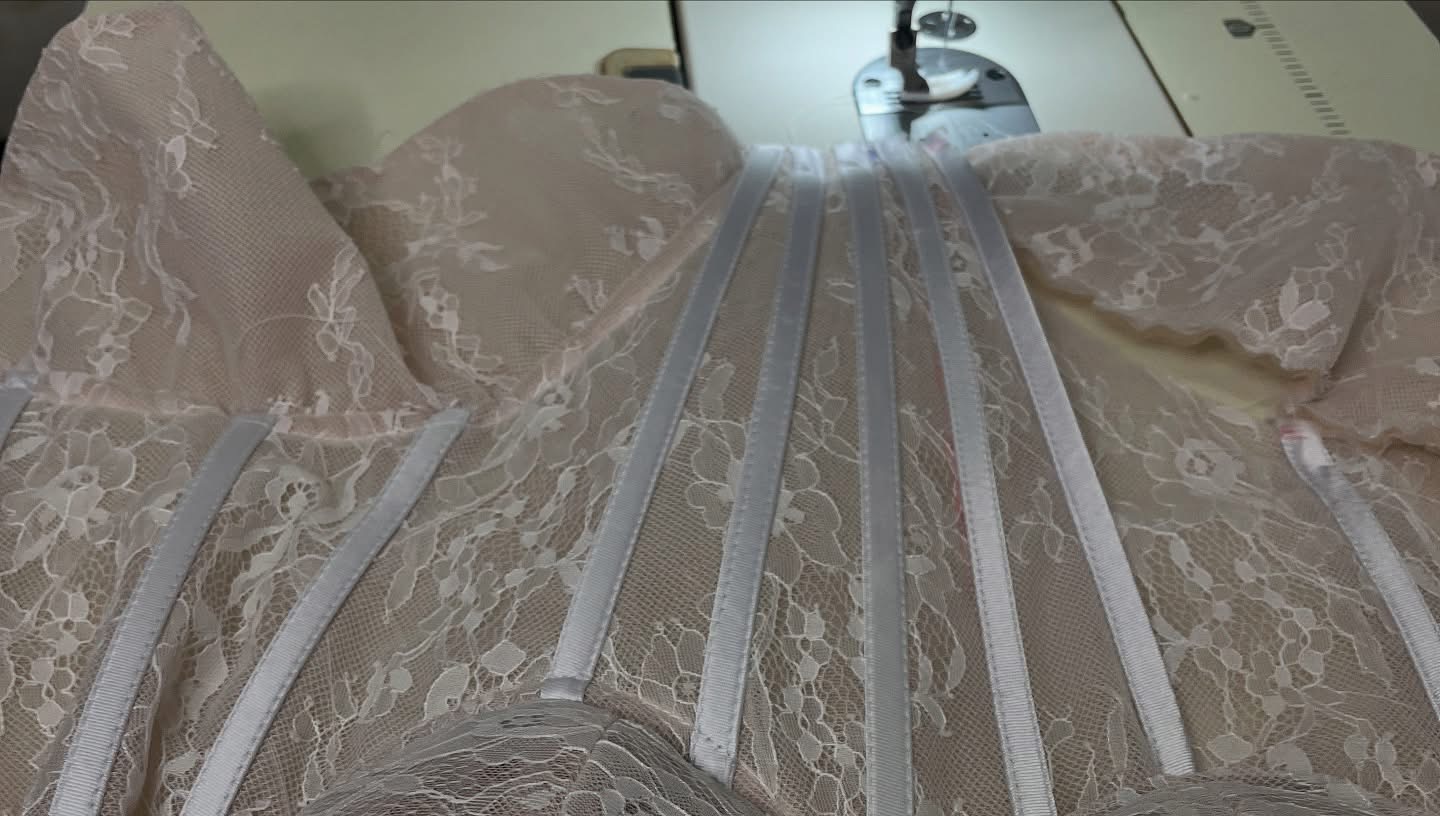 Lace bodice with visible structural channels on a sewing worktable.