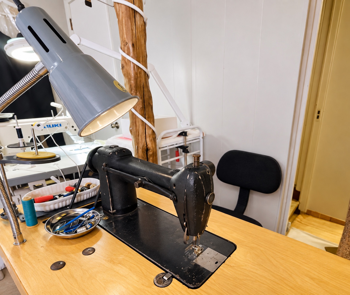 Black specialty sewing machine on a wooden worktable.